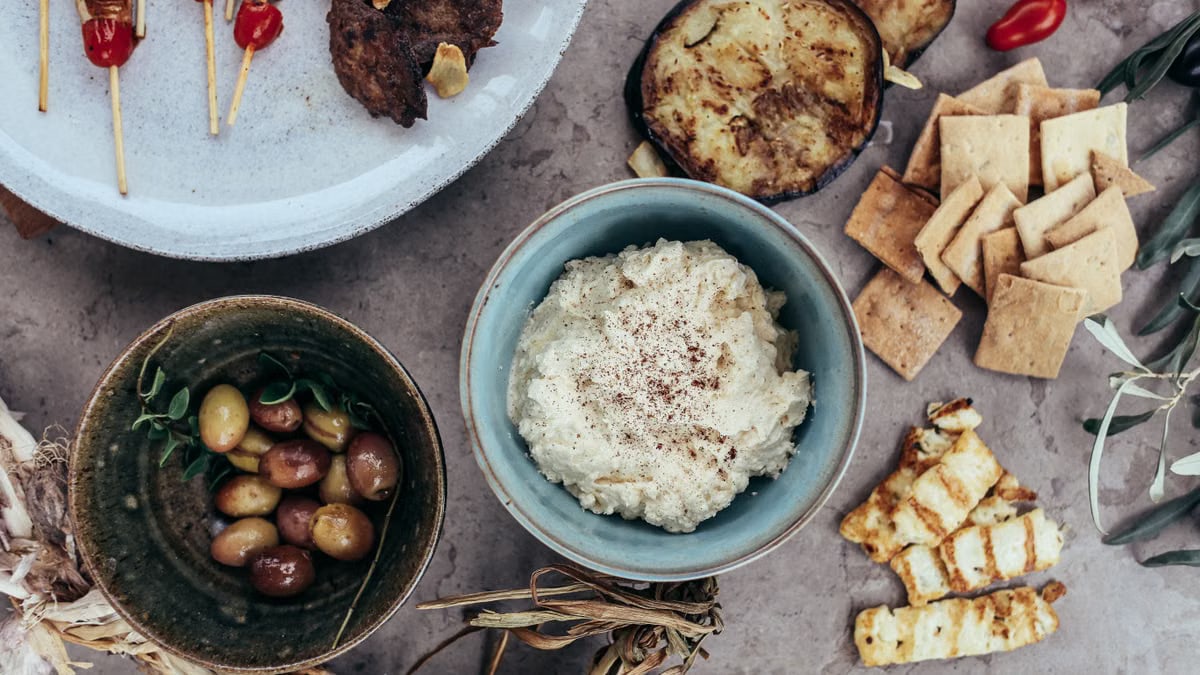 A variety of Mediterranean appetizers featuring hummus, olives, and grilled vegetables set on a rustic table.